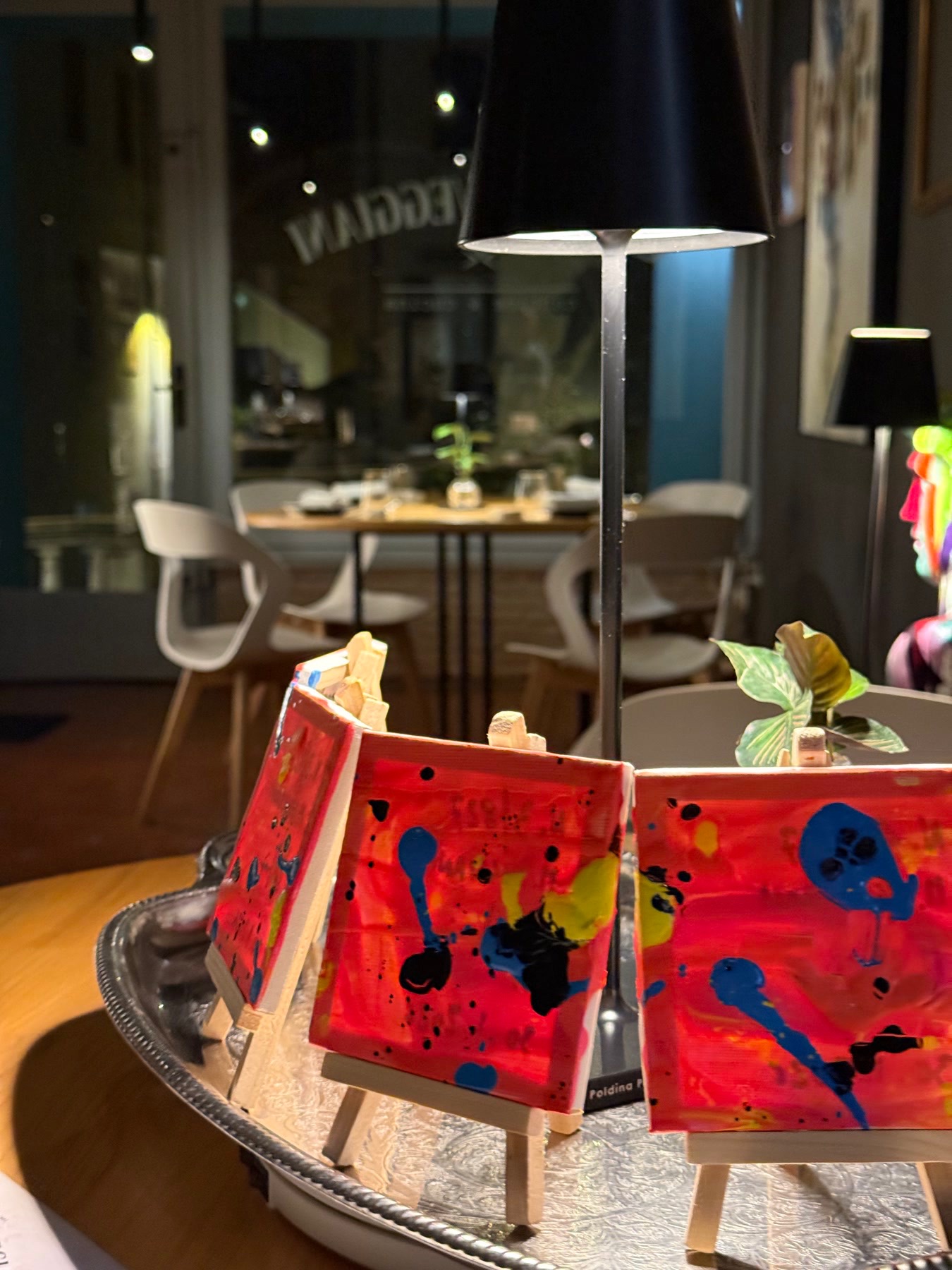 Piccole tele dipinte su cavalletti da tavolo nella sala di Cantina Veggiani